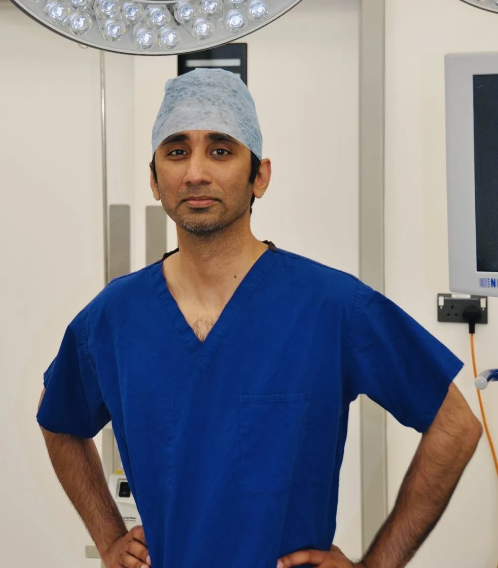 Mr Srikanth Reddy, consultant orthopaedic surgeon, standing in an operating theatre in blue scrubs